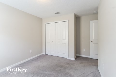 A bedroom with a white door and carpeted floor.