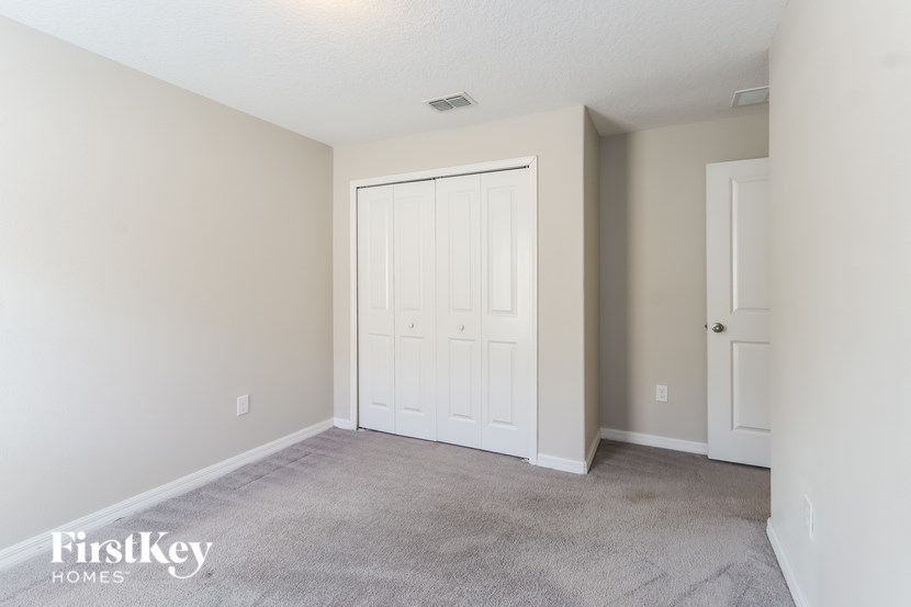 A bedroom with a white door and carpeted floor.
