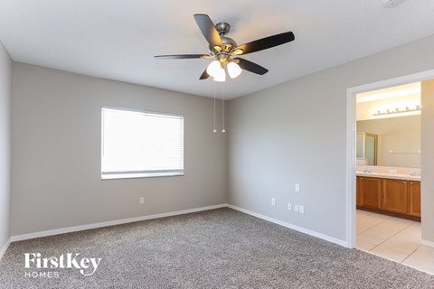 the master bedroom has a ceiling fan and a carpet