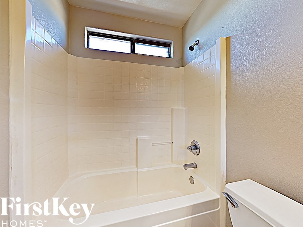 a bathroom with a tub and a toilet and a window
