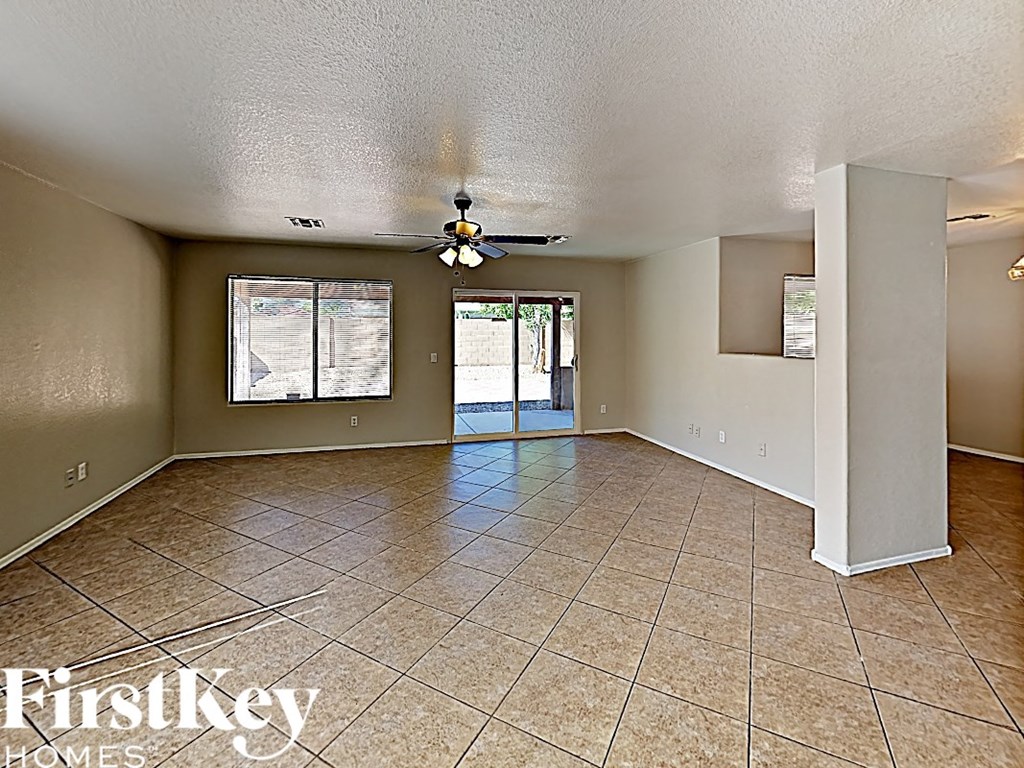 an empty living room with tile flooring and a ceiling fan