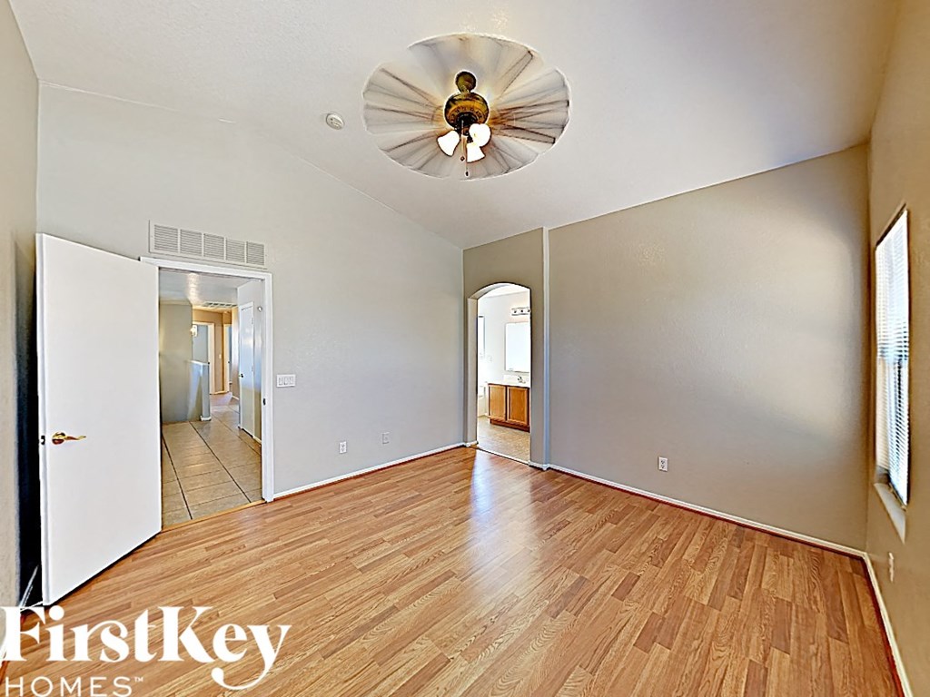 a spacious living room with hardwood flooring and a ceiling fan