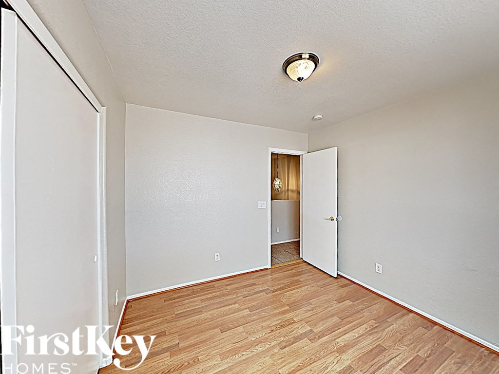 an empty room with wood flooring and a door to a hallway