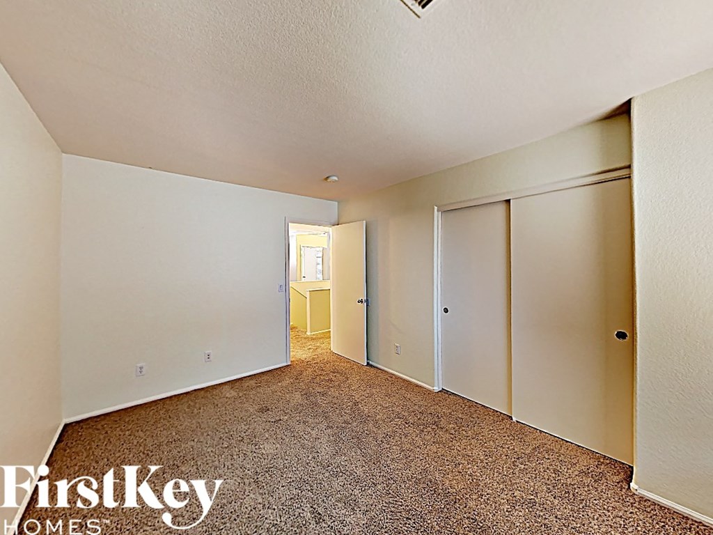 an empty bedroom with closet doors and carpeting
