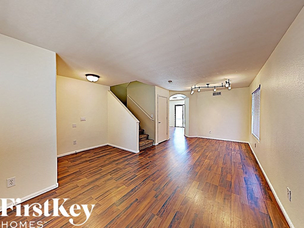 a spacious living room with hardwood flooring and a door to a staircase