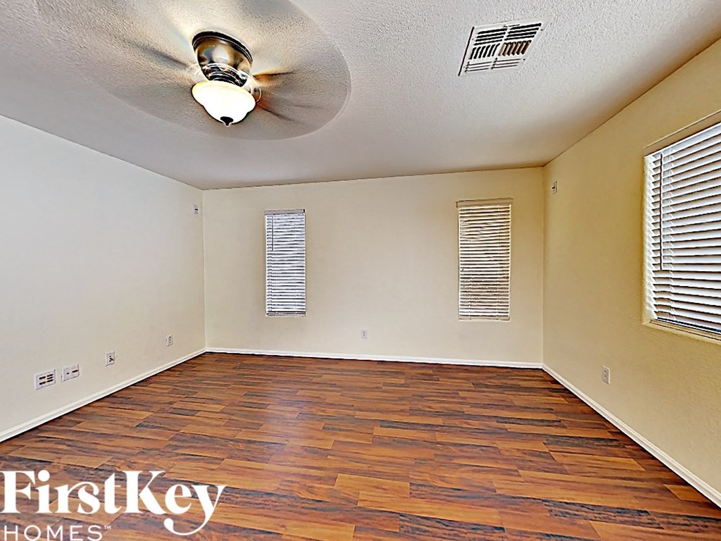an empty living room with wood flooring and a ceiling fan
