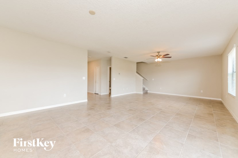 A spacious empty room with a ceiling fan and light fixture.