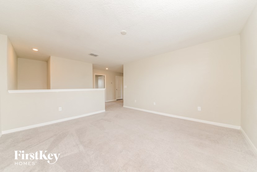 A spacious empty room with a carpeted floor and white walls.