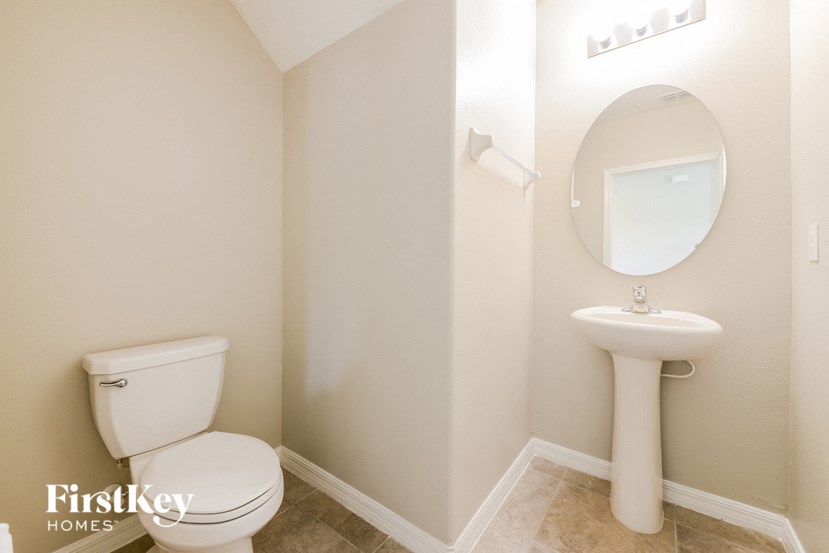 A white toilet sits next to a pedestal sink in a small bathroom.