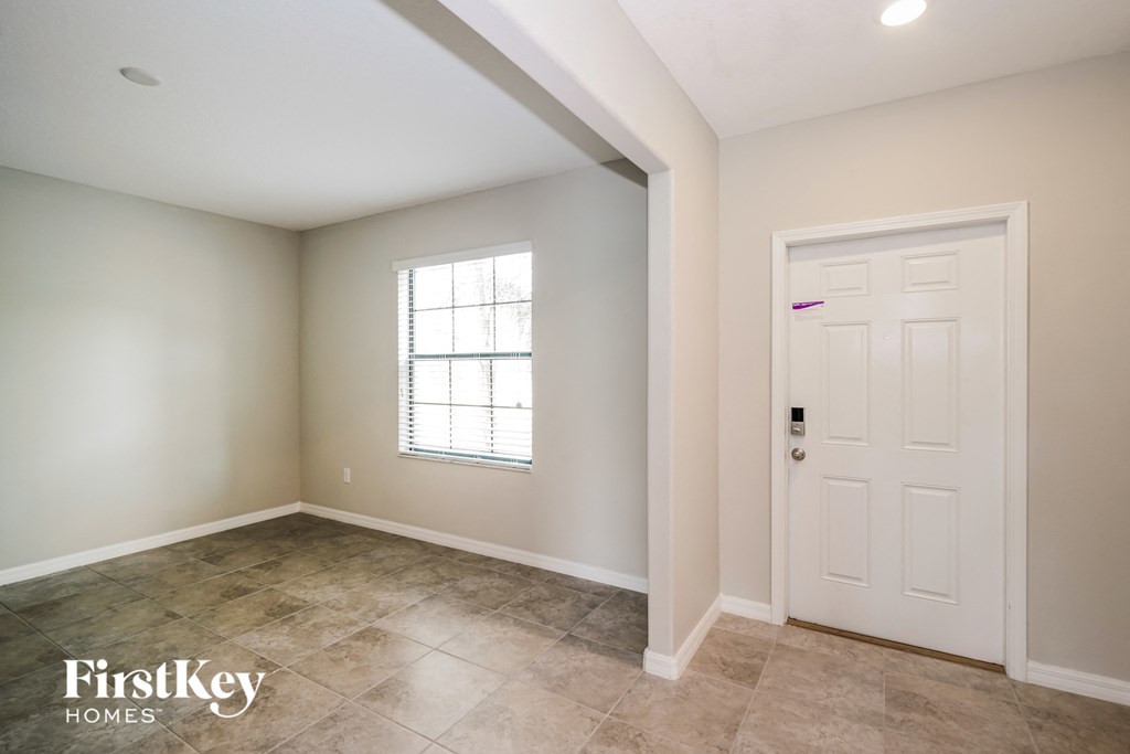 A room with a white door and a window with white blinds.