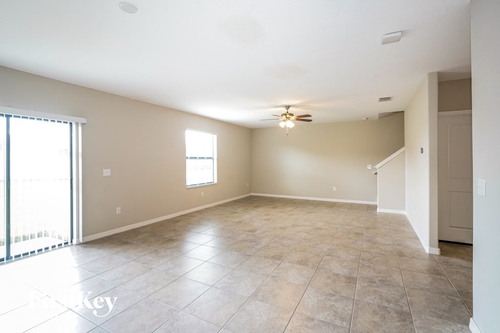 A spacious room with a ceiling fan and tile flooring.