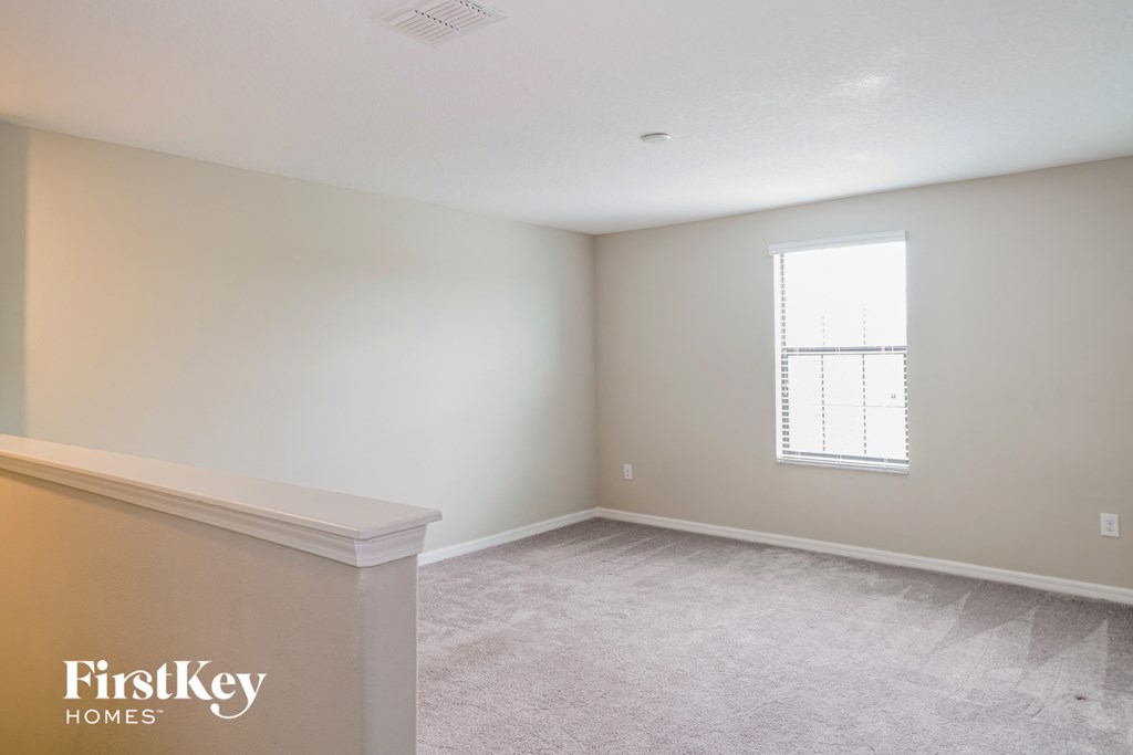 A room with a carpeted floor and a window with blinds.