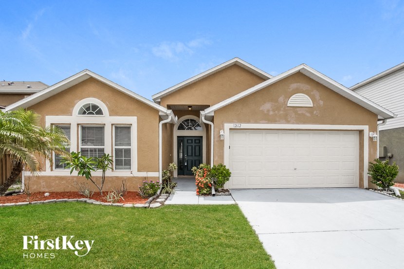 a beige house with a garage door and a lawn