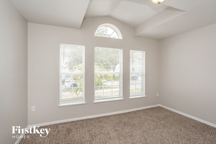 the living room of a home with three windows and carpet