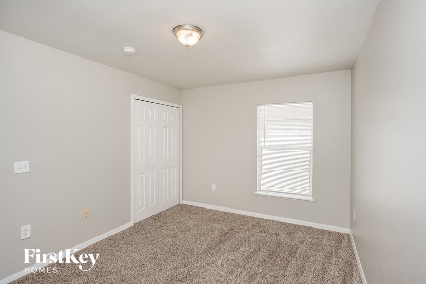 a bedroom with carpet and a white door and window