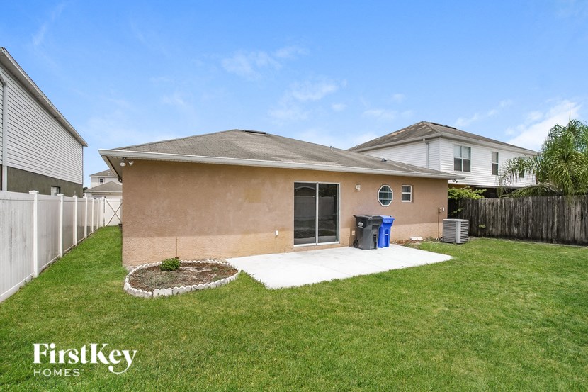 a small brown house with a lawn and a white fence