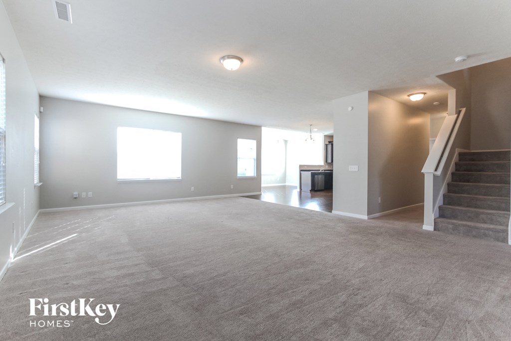 A spacious living room with a staircase leading to the upper level.