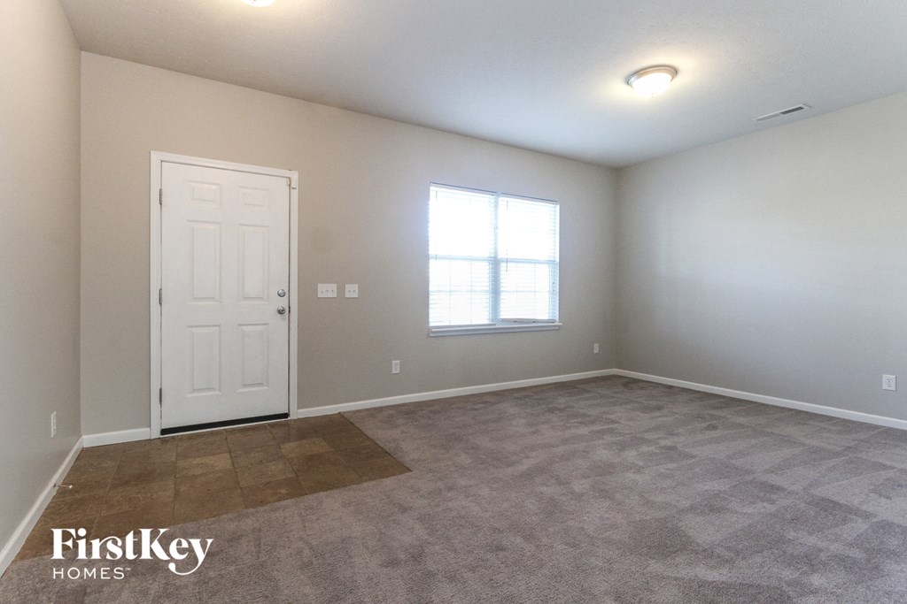 A room with a door, a window, and a carpeted floor.