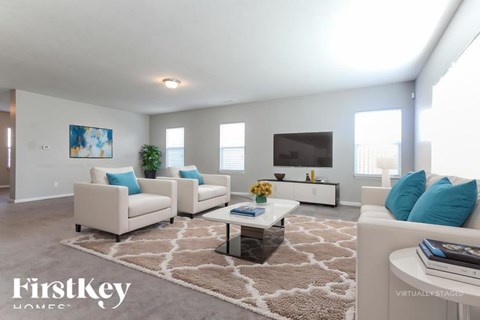 A living room with a couch, two chairs, a coffee table, and a painting on the wall.