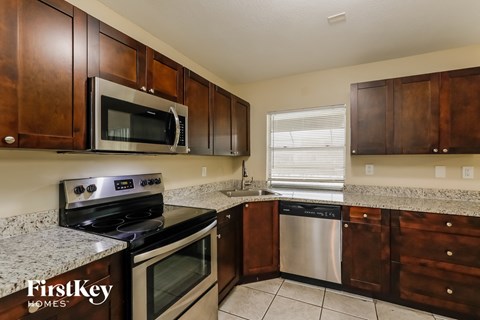 A kitchen with wooden cabinets and a stainless steel dishwasher.