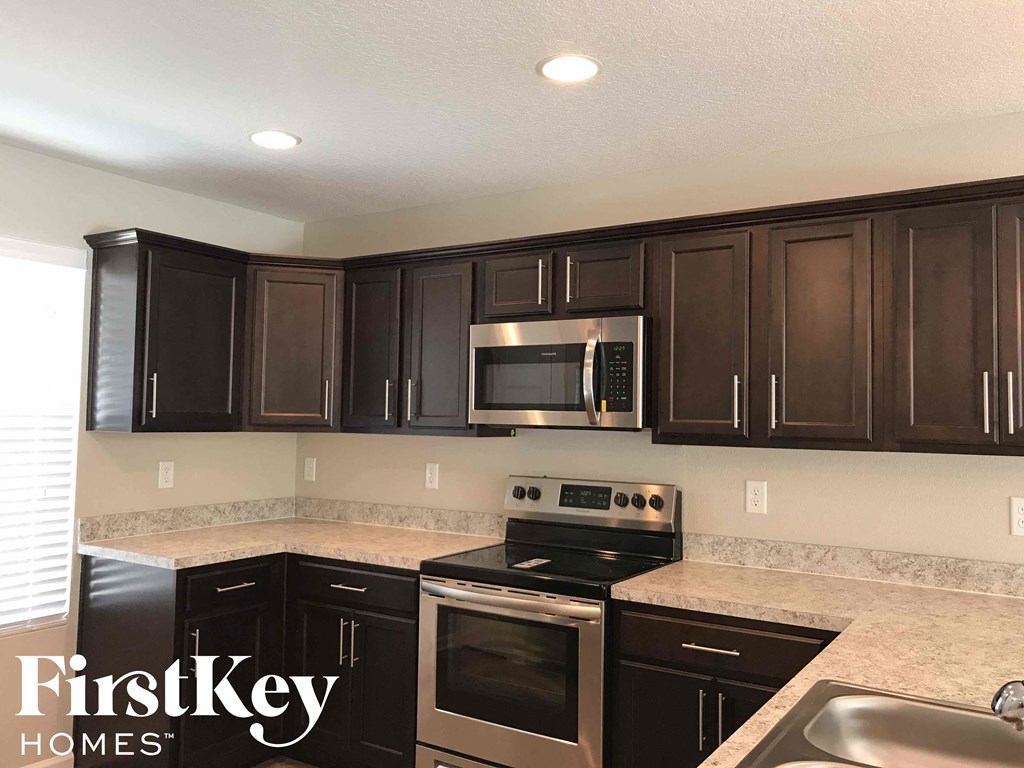 A kitchen with dark brown cabinets and stainless steel appliances.