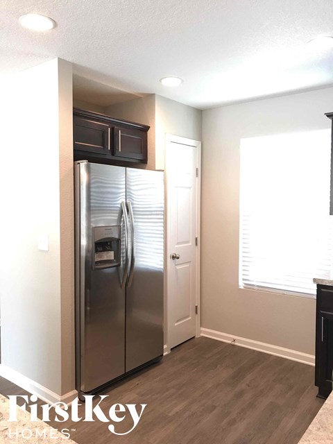 A stainless steel refrigerator in a kitchen with a FirstKey Homes logo.