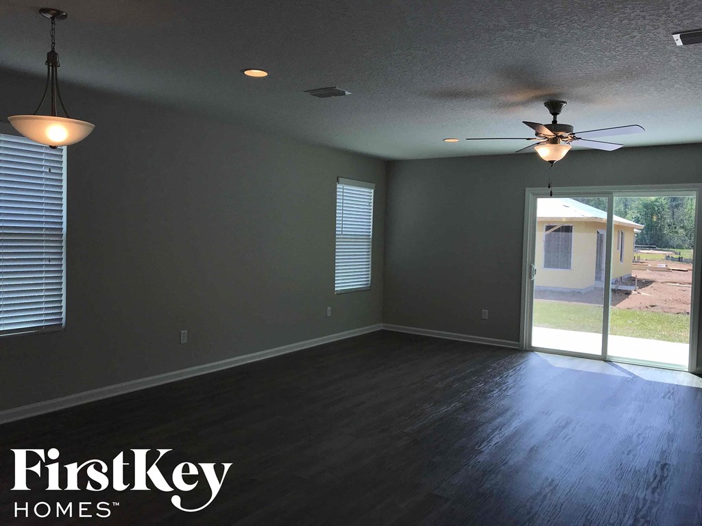 A room with a ceiling fan and sliding glass doors.