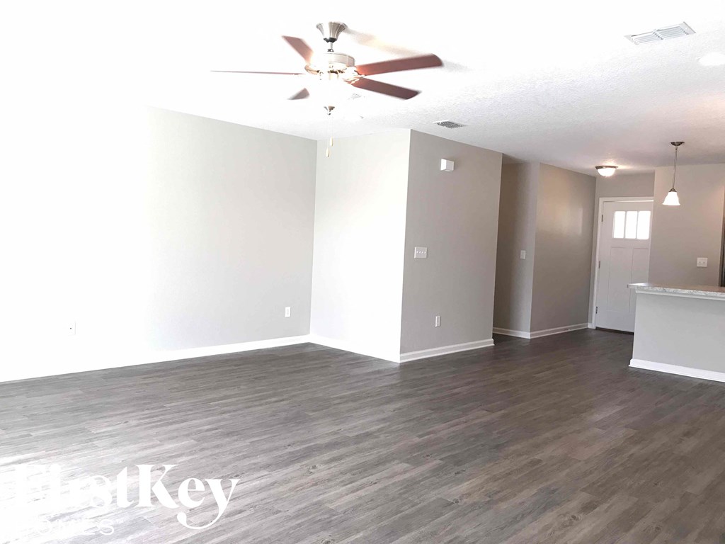 A room with a ceiling fan and wooden flooring.