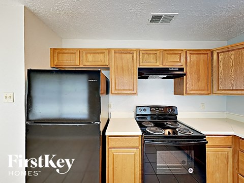a kitchen with wood cabinets and a black refrigerator