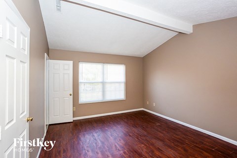 a bedroom with wood floors and a white door and a window