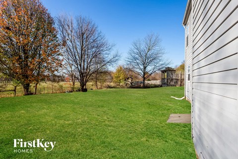 a backyard with green grass and a white house