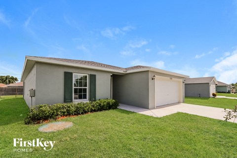 a beige house with a lawn and a driveway