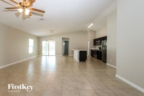 an empty living room and kitchen with a ceiling fan