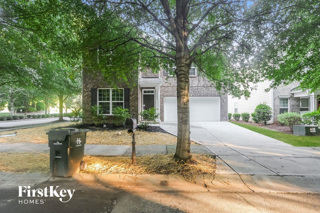 a house with a driveway and a tree in front of it