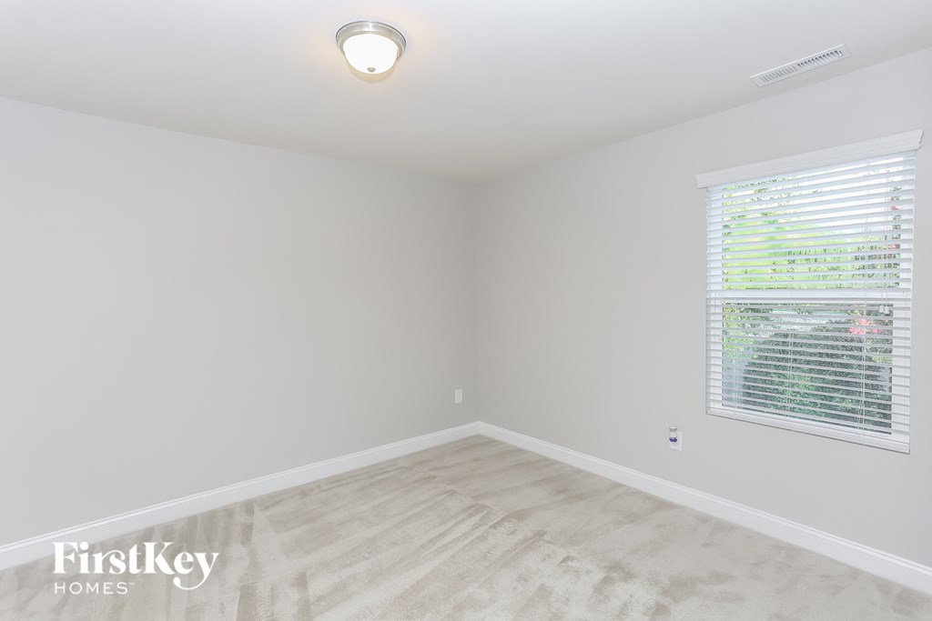 a bedroom with a large window and white walls and wood floors