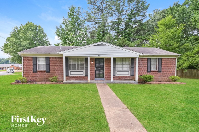 A brick house with a porch and a sidewalk in front.