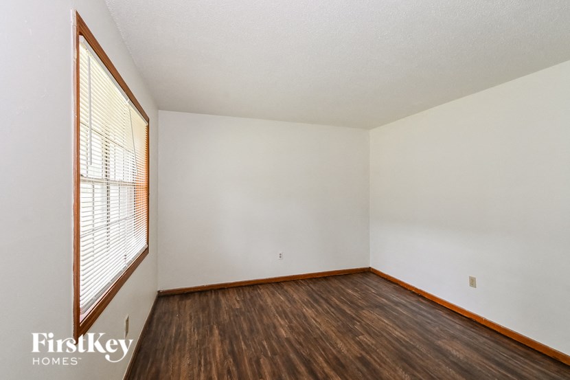 A room with wooden floors and a window with blinds.