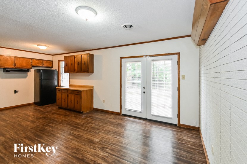 A kitchen area with wooden floors and a black refrigerator.