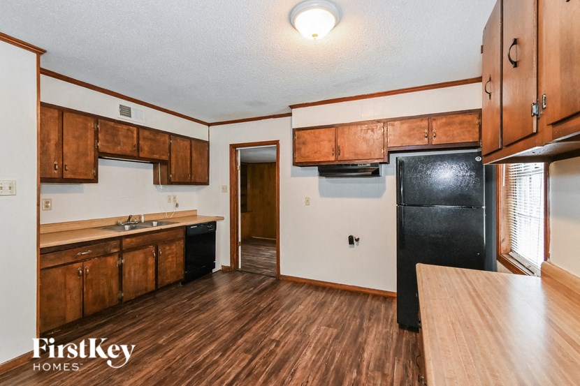 A kitchen with wooden cabinets and a black refrigerator.