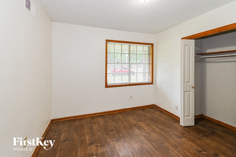 A room with wooden floors and a window with blinds.