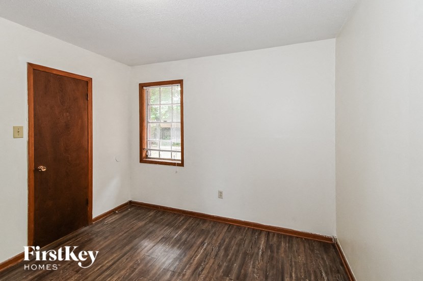 A room with a wooden floor, a door and a window.