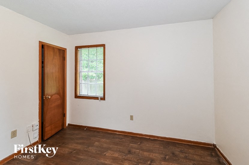 A room with a wooden floor and a window with blinds.