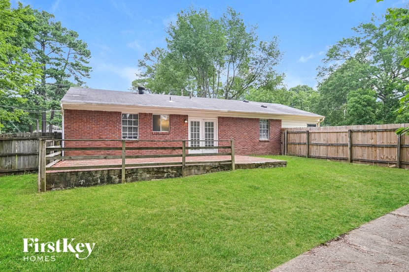 A brick house with a wooden fence and a green lawn.