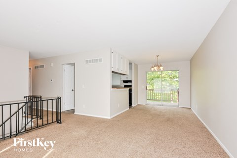 A spacious living room with a balcony overlooking a green area.
