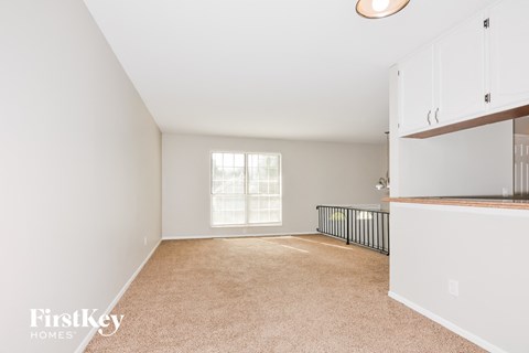 A spacious room with white walls and a window with blinds.
