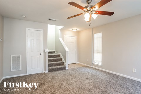 a living room with a ceiling fan and stairs