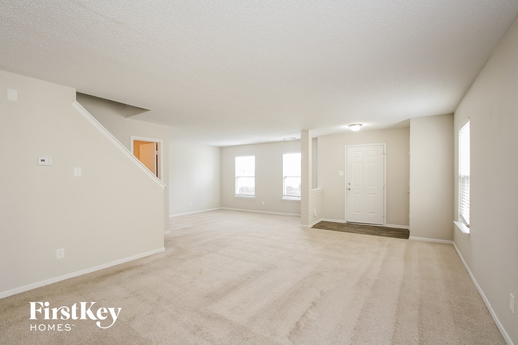 A spacious room with a carpeted floor and a staircase leading to another level.