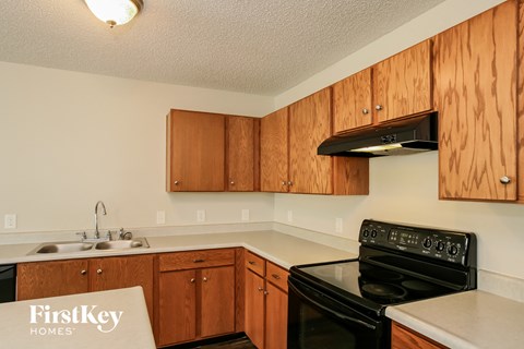 A kitchen with wooden cabinets and a black stove top oven.