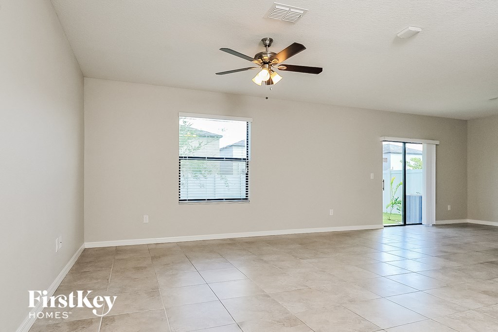 an empty living room with a ceiling fan and tile floor