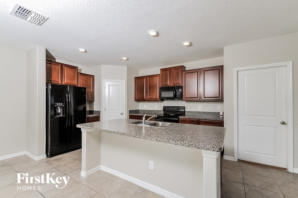 a kitchen with a granite counter top and a black refrigerator